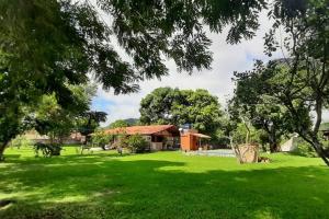 ein Haus auf einem Feld mit einem Hof mit grünem Gras in der Unterkunft Sítio Vivendo & Aprendendo in Tanguá