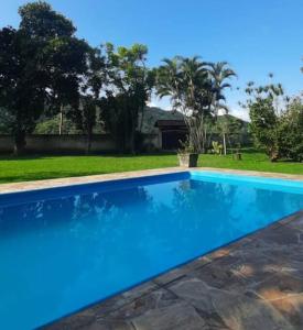 een groot blauw zwembad in een tuin bij Sítio Vivendo & Aprendendo in Tanguá