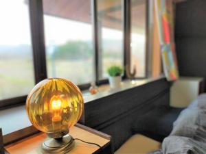 een lamp op een tafel in een kamer met ramen bij ゲストハウス　アンブレラ in Soma