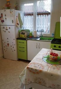 eine Küche mit einem Kühlschrank und einem Tisch mit einer Schale Obst in der Unterkunft Casa Emil in Botuş