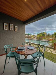 - une table et des chaises sur une terrasse avec piscine dans l'établissement Gamboa Patacho Apto 002 Bloco B - ER Hospedagens, à Porto de Pedras