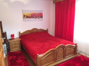 Schlafzimmer mit einem roten Bett und roten Vorhängen in der Unterkunft Casa Emil in Botuş