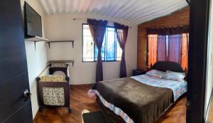 a bedroom with a bed and a chair and windows at Montañita del Río in Aratoca