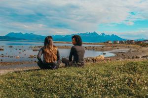 un hombre y una mujer sentados en la orilla de una playa en Hotel Los Ñires en Ushuaia