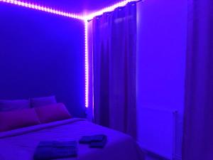 a bedroom with a bed with purple lights on it at Guest Room avec SDB privée près de Paris, Roissy CDG et du village Olympique in Persan