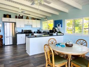 a kitchen with a table and chairs and a kitchen with blue walls at Stunning Ocean Views - Whale House Hawaii in Hawaiian Paradise Park