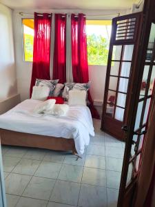a bedroom with a large bed with red curtains at Maison de 2 chambres avec vue sur la mer jardin clos et wifi a saint joseph in Saint-Joseph