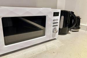 a white microwave oven sitting on top of a counter at Garden Eleven - Duplex City Centre Apartment in Hemel Hempstead