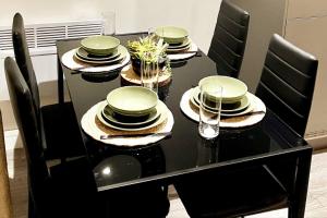 una mesa negra con sillas negras y platos verdes. en Garden Eleven - Duplex City Centre Apartment en Hemel Hempstead