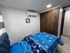 een slaapkamer met een blauw bed en een houten deur bij Apartamento nuevo en Barranquilla in Barranquilla