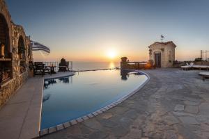 a swimming pool with the sunset in the background at Four Seasons Stonework Castle in Lagonissi