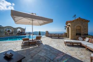 a patio with an umbrella and a swimming pool at Four Seasons Stonework Castle in Lagonissi