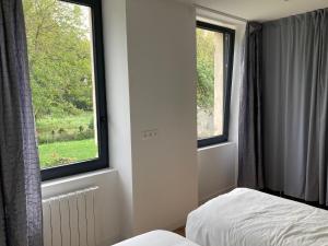 a bedroom with two windows and a bed in it at Gîte de Bel Oeuvre in Moulins-sur-Orne