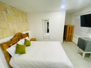 a bedroom with a white bed and a television at Casa Playa James in Los Arrayanes