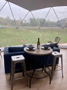 una mesa con una botella de vino y una tienda de campaña en Open Sky Glamping Kawartha Dome, en Marmora