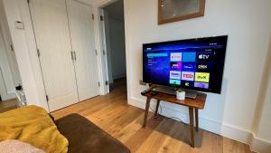 a living room with a flat screen tv on a wall at Modern & stylish 1 bedroom flat in London