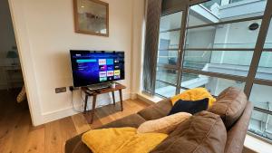 a living room with a couch and a flat screen tv at Modern & stylish 1 bedroom flat in London