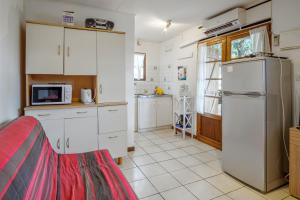 a kitchen with white cabinets and a refrigerator at Bungalow charmant à Saint Paul avec vue sur la mer in Fleurimont