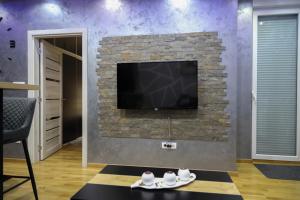 un salon avec une télévision sur un mur en briques dans l'établissement MYSTIC, à Subotica