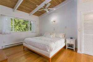 a white bedroom with a bed and a window at West Coast Contemporary Home - Central Lonsdale in North Vancouver