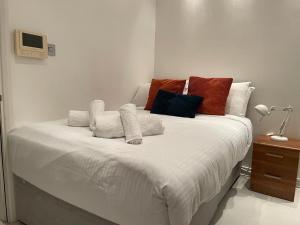 a bedroom with a white bed with colorful pillows at Smithfield St Paul Farringdon Central London Apartment in London