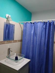 a bathroom with a blue shower curtain and a sink at Casa del Cedro in Tuxtla Gutiérrez