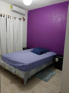 a bedroom with a purple wall and a bed at Casa del Cedro in Tuxtla Gutiérrez
