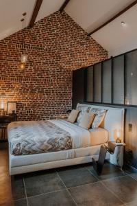 Un dormitorio con una pared de ladrillo y una cama grande en Queen's Avenue, Wellness and free station E-Car, en Spa