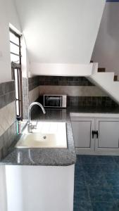 a kitchen with a sink and a microwave at 2 bedrooms house with furnished terrace and wifi at Fond du Sac 5 km away from the beach in Fond du Sac