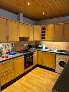 uma cozinha com armários de madeira, um lavatório e uma máquina de lavar louça em Cosy home in a beautiful valley em Tipperary