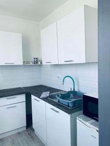 a white kitchen with a sink and white cabinets at Füred Apartman in Balatonfüred