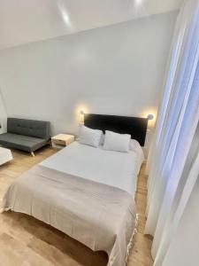 a white bedroom with a bed and a couch at Lofts IFEMA in Madrid