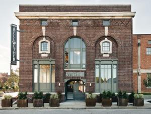 a red brick building with large windows and plants at The Bellwether Hotel in Louisville