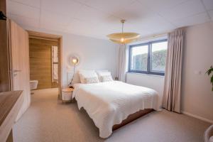 una camera bianca con un letto e una finestra di Le Terrier Ovifat - Appartement entier Familial - Sauna & Massage a Ovifat
