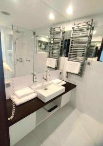 Un baño blanco con lavabo y ducha. en Prywatny Apartament Marine Hotel, en Kołobrzeg