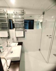 Un baño blanco con ducha y lavabo. en Prywatny Apartament Marine Hotel, en Kołobrzeg