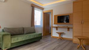 a living room with a green couch and a tv at LOTUSPARK HOTEL in Bursa