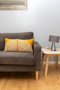 a gray couch with a yellow pillow next to a table at Newly Refurbished 2BD Flat wParking - Peckham! in London