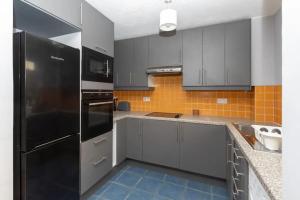 a kitchen with gray cabinets and a black refrigerator at Newly Refurbished 2BD Flat wParking - Peckham! in London