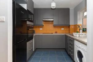a kitchen with gray cabinets and a black refrigerator at Newly Refurbished 2BD Flat wParking - Peckham! in London