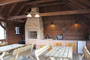 a dining room with wooden tables and a brick oven at Domki Letniskowe FRIDA in Wiele