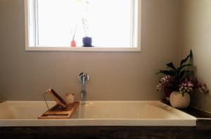 a bath tub in a bathroom with a window at Coastal Gem in Port Waikato