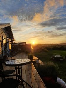 a deck with a table and chairs at sunset at Coastal Gem in Port Waikato