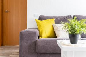 un sofá gris con almohadas amarillas en la sala de estar en Luxe - Penthouse - 2BR - Seaview - Beach - Parking, en Creixell