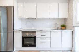 cocina con armarios blancos y nevera de acero inoxidable en Luxe - Penthouse - 2BR - Seaview - Beach - Parking, en Creixell