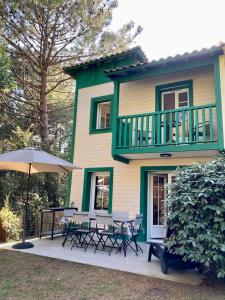 a house with a deck with tables and an umbrella at DOMAINE DU GOLF LACANAU Maison 3 ch, piscine 500 m², Golf, proche océan in Lacanau