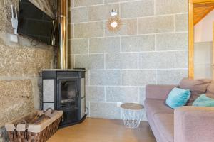 a living room with a couch and a fireplace at Casa Rústica T2 com Salamandra e Cozinha - Seia - Serra da Estrela - Casa do Loureiro II in Seia +17 photos