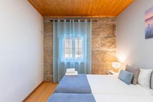 a bedroom with a large bed and a window at Casa Rústica T2 com Salamandra e Cozinha - Seia - Serra da Estrela - Casa do Loureiro II in Seia