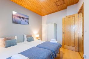 a bedroom with two beds and a wooden ceiling at Casa Rústica T2 com Salamandra e Cozinha - Seia - Serra da Estrela - Casa do Loureiro II in Seia