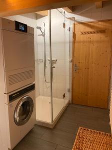 uma casa de banho com uma máquina de lavar roupa e um chuveiro em Attic in the Alps em Luzein